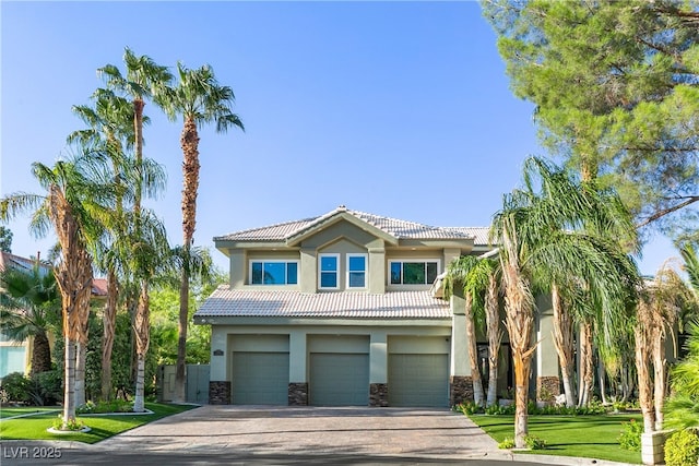 view of front of property featuring a garage, a tile roof, stone siding, driveway, and stucco siding