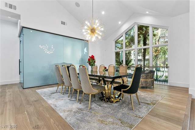 dining area featuring light wood-type flooring, high vaulted ceiling, visible vents, and a chandelier