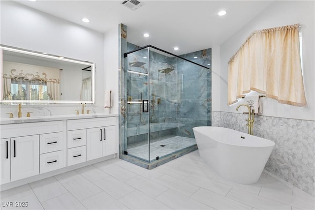 full bathroom with a freestanding tub, a sink, visible vents, a shower stall, and double vanity