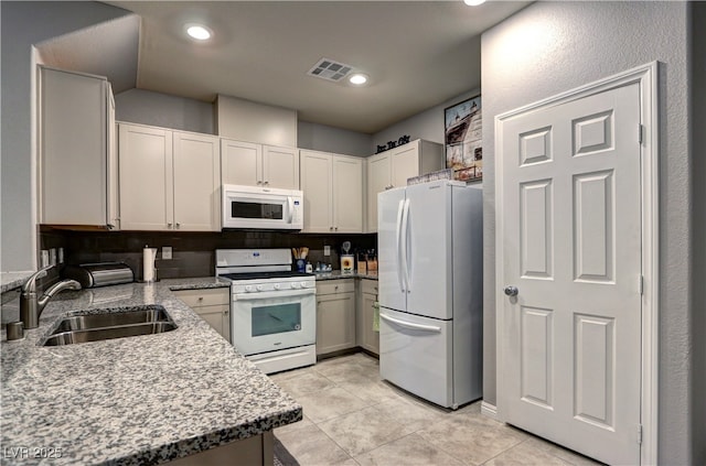 kitchen with white appliances, visible vents, light stone countertops, a sink, and light tile patterned flooring