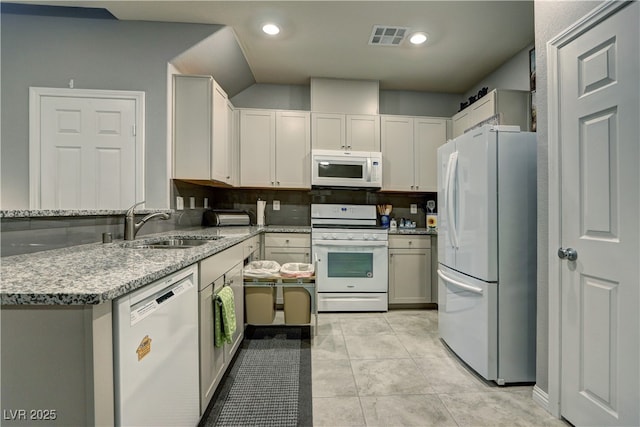 kitchen featuring light stone counters, white appliances, a sink, visible vents, and decorative backsplash