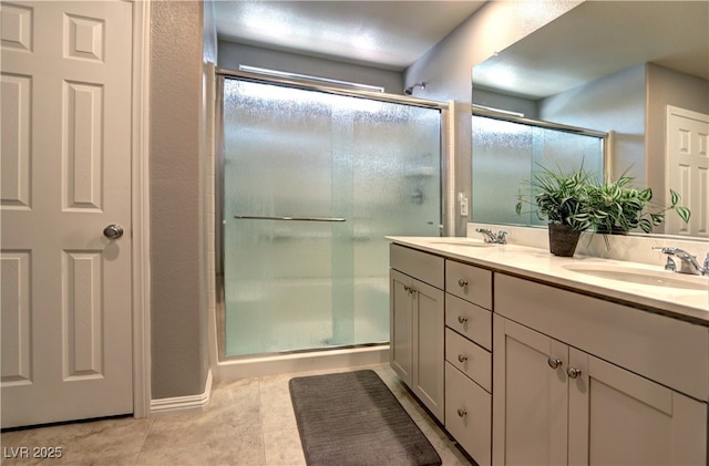 bathroom with double vanity, a shower with door, a sink, and tile patterned floors