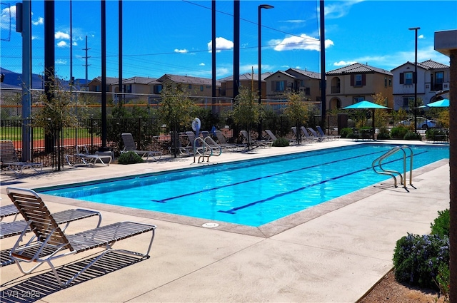 community pool with a residential view, fence, and a patio