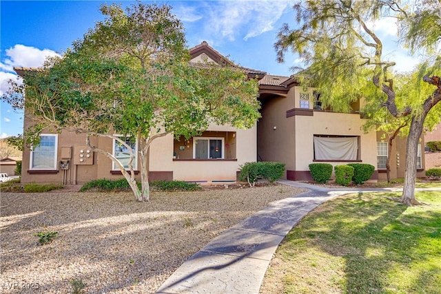 view of front of property with a front yard, a tiled roof, and stucco siding