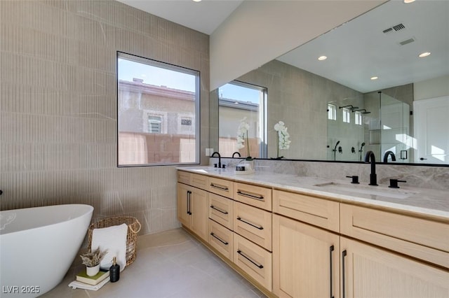 full bath with a walk in shower, a sink, visible vents, tile walls, and double vanity