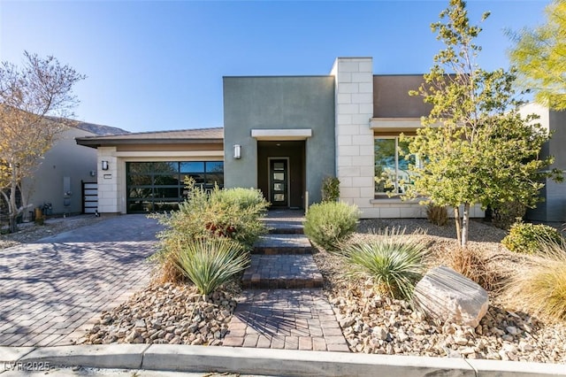 view of front of property featuring a garage, decorative driveway, and stucco siding