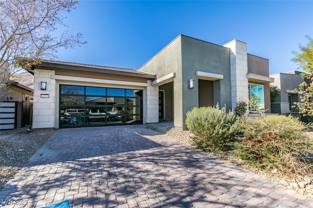 contemporary home featuring decorative driveway and stucco siding