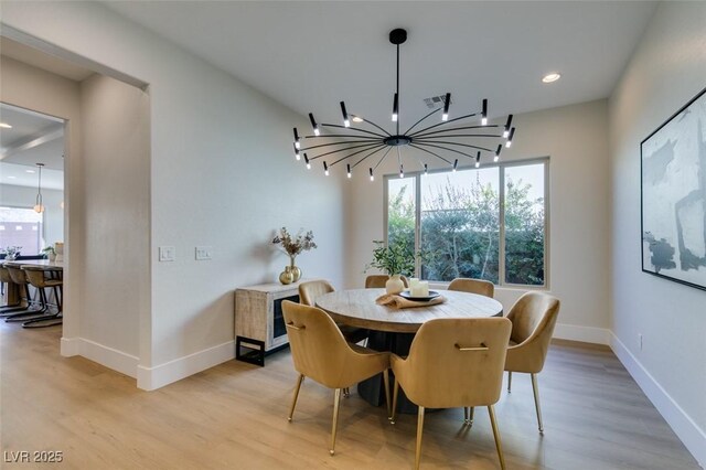 dining area featuring a chandelier, light wood-style flooring, a wealth of natural light, and baseboards