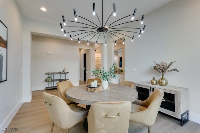 dining space featuring baseboards, light wood finished floors, and track lighting