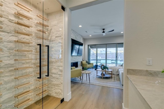 interior space featuring a fireplace, recessed lighting, a ceiling fan, wood finished floors, and walk in shower