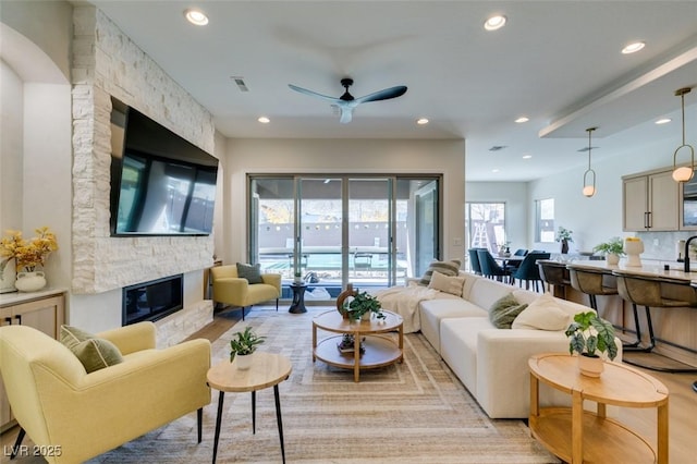 living area featuring a ceiling fan, recessed lighting, light wood-style floors, and a fireplace