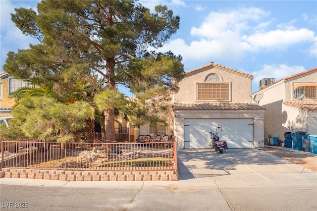 mediterranean / spanish-style house featuring concrete driveway, a tile roof, fence, and stucco siding