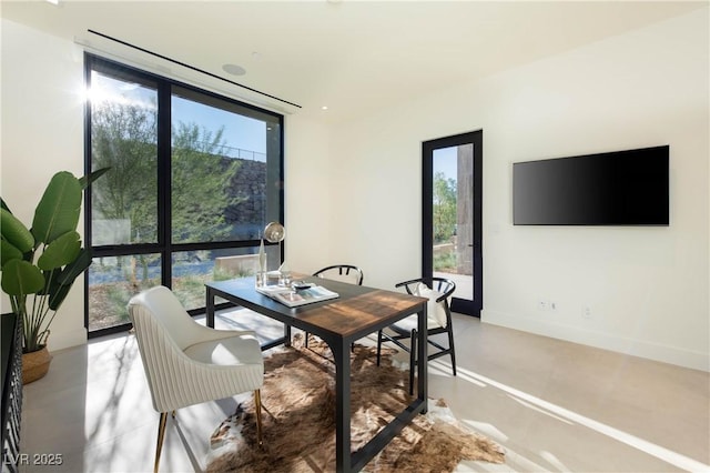 home office with baseboards, floor to ceiling windows, and concrete flooring