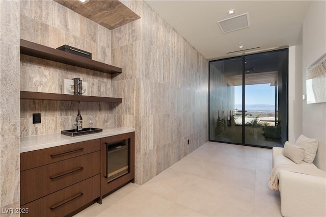 bar featuring a dry bar, visible vents, a wall of windows, and tile walls