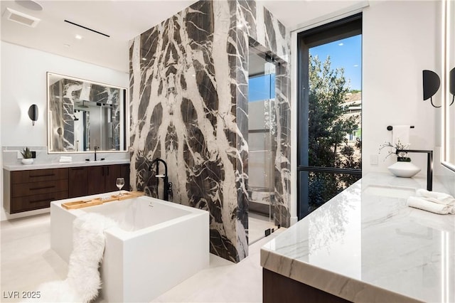 bathroom with a freestanding bath, visible vents, and vanity