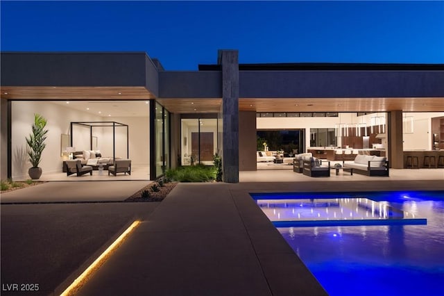 pool at twilight with outdoor lounge area, an outdoor pool, and a patio