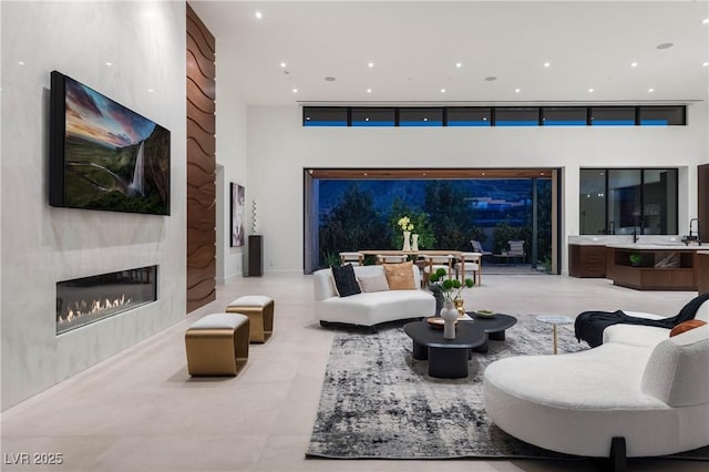 living room featuring a high ceiling, a glass covered fireplace, and recessed lighting