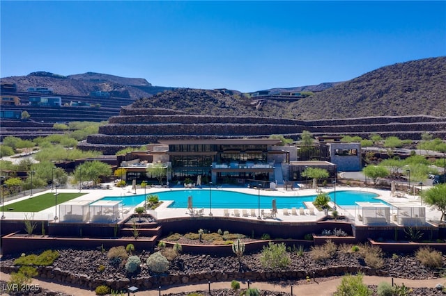 community pool with a mountain view, fence, and a patio