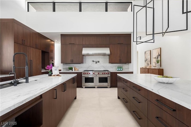 kitchen with range with two ovens, a sink, range hood, tasteful backsplash, and modern cabinets