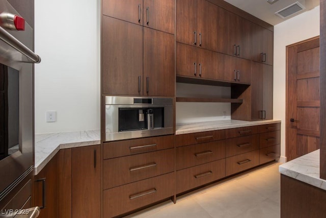 kitchen with light stone counters, oven, visible vents, open shelves, and modern cabinets