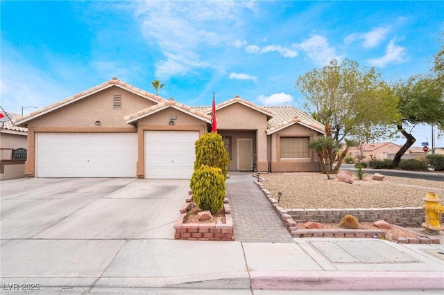 view of front of property with stucco siding, a garage, driveway, and a tile roof