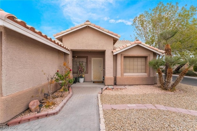 property entrance featuring stucco siding and a tile roof