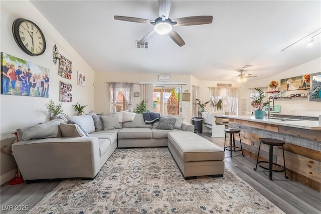 living area featuring lofted ceiling, light wood-style floors, visible vents, and ceiling fan