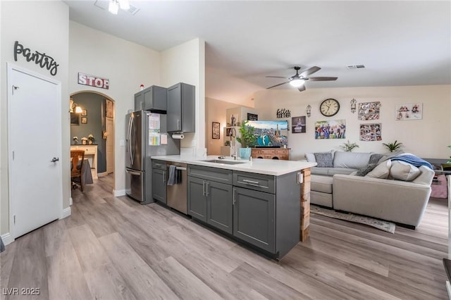 kitchen with a peninsula, gray cabinets, arched walkways, stainless steel appliances, and open floor plan