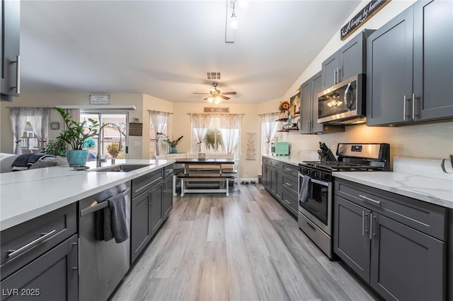 kitchen featuring a ceiling fan, visible vents, light wood-style flooring, a sink, and stainless steel appliances