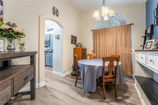 dining space featuring a notable chandelier, arched walkways, light wood-style floors, and baseboards