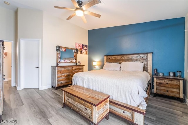 bedroom with a ceiling fan, wood finished floors, baseboards, visible vents, and lofted ceiling