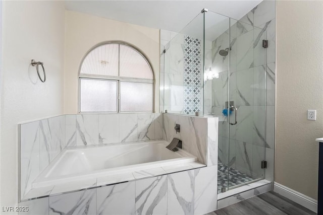 full bath featuring a garden tub, a textured wall, and a marble finish shower