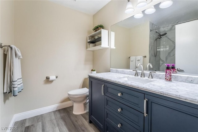 bathroom featuring toilet, wood finished floors, a marble finish shower, baseboards, and vanity