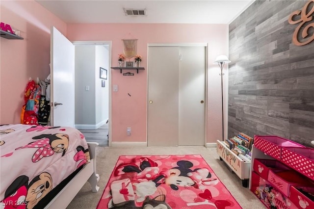 bedroom with visible vents, a closet, wood walls, light carpet, and an accent wall