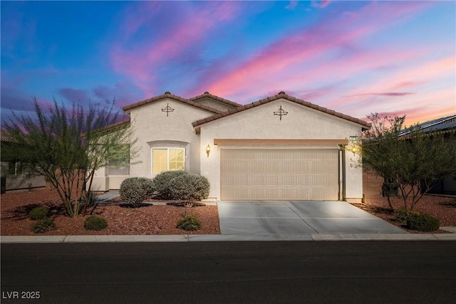 mediterranean / spanish home with driveway, an attached garage, a tile roof, and stucco siding