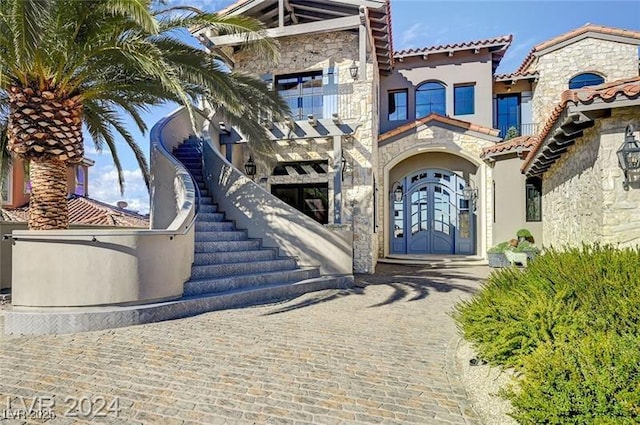 doorway to property featuring stone siding, a tiled roof, and stucco siding