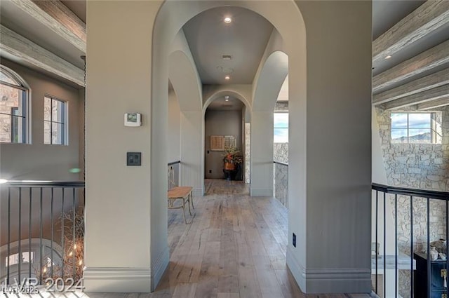 corridor with arched walkways, baseboards, and wood finished floors