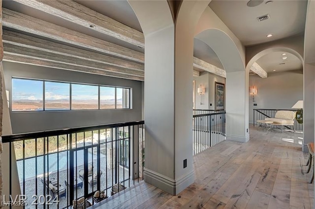 hallway with visible vents, light wood-style flooring, and baseboards