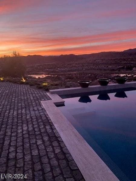 pool at dusk with a patio area and a mountain view