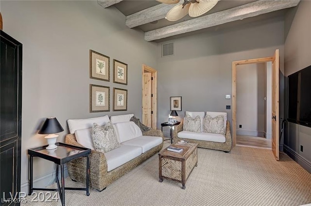 living area with a ceiling fan, visible vents, beamed ceiling, and baseboards