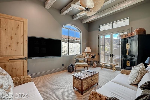 living room featuring plenty of natural light, a ceiling fan, carpet flooring, and beamed ceiling