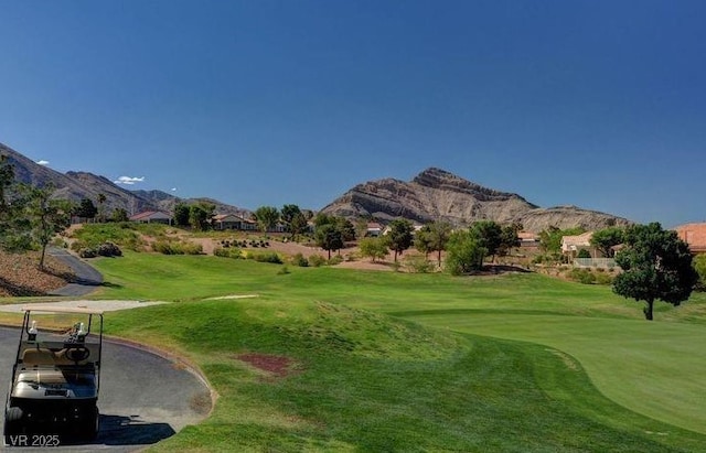 view of home's community featuring a lawn, golf course view, and a mountain view