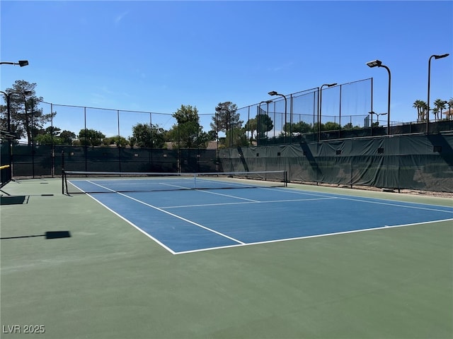 view of tennis court with community basketball court and fence