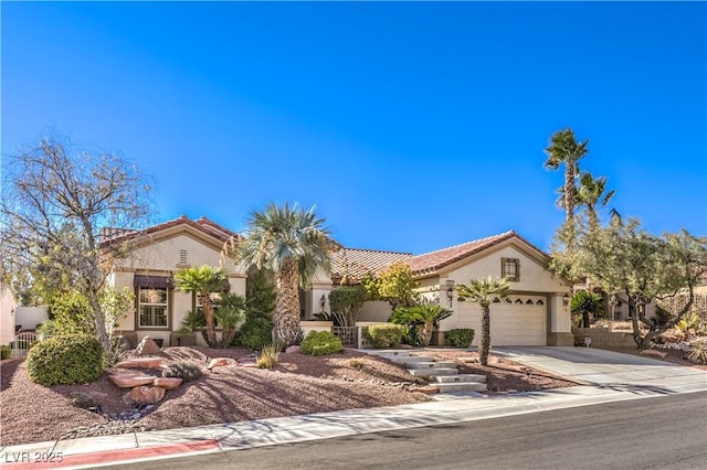 mediterranean / spanish house featuring driveway, a tiled roof, an attached garage, and stucco siding