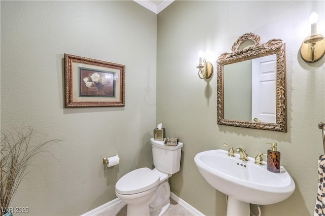 half bath featuring a sink, toilet, and baseboards