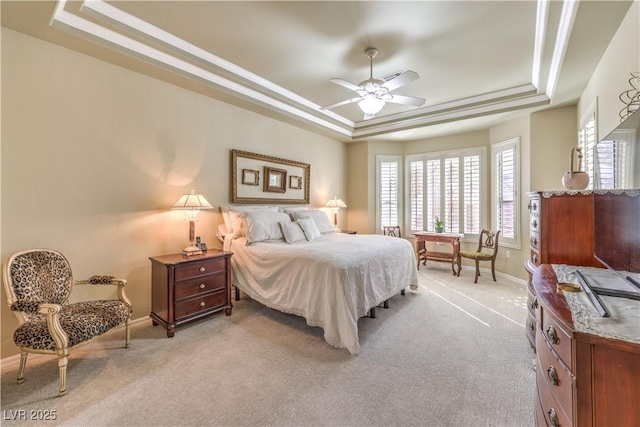 bedroom with baseboards, a tray ceiling, ornamental molding, and light colored carpet