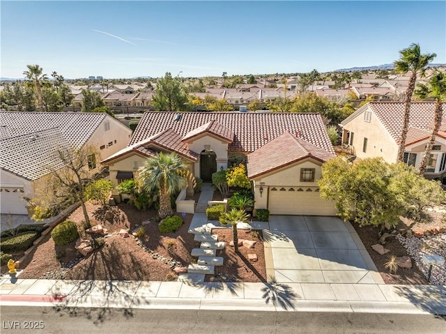 mediterranean / spanish house with concrete driveway, a tile roof, a residential view, an attached garage, and stucco siding