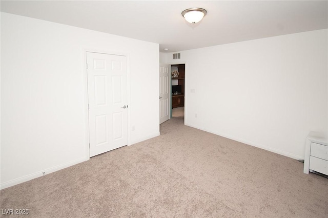 carpeted spare room featuring visible vents and baseboards