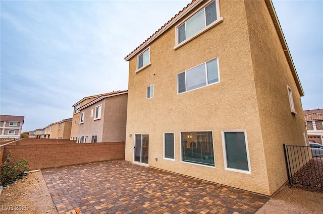 back of house with a patio area, fence, and stucco siding