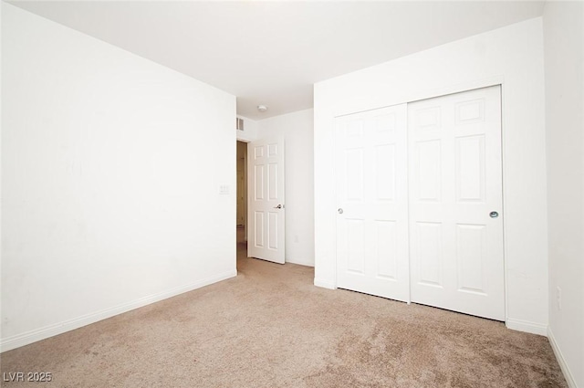 unfurnished bedroom featuring light carpet, baseboards, and a closet